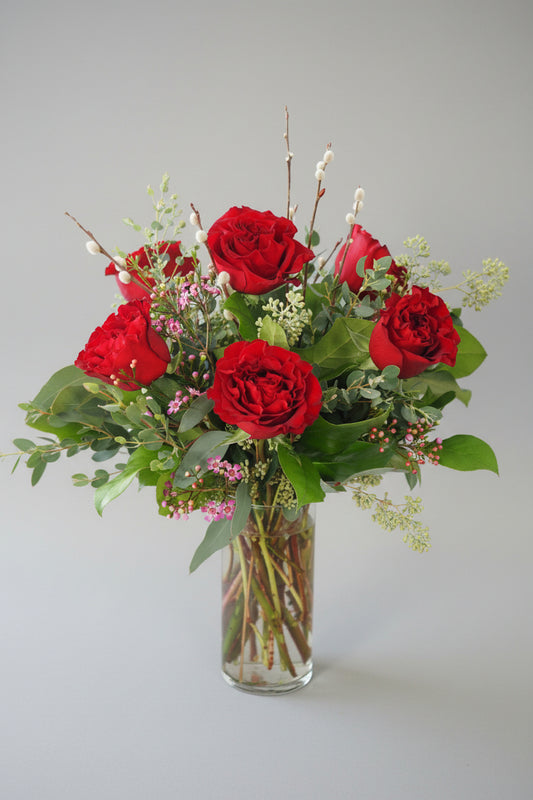 Bouquet of red roses with greenery on a white background