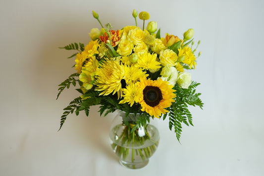 Bouquet of yellow flowers with green leaves on a light background