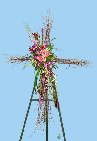 Floral arrangement on a decorative cross with a white background