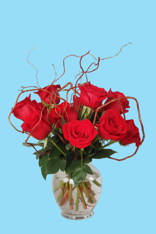 Bouquet of red roses in a clear vase with a natural wood background