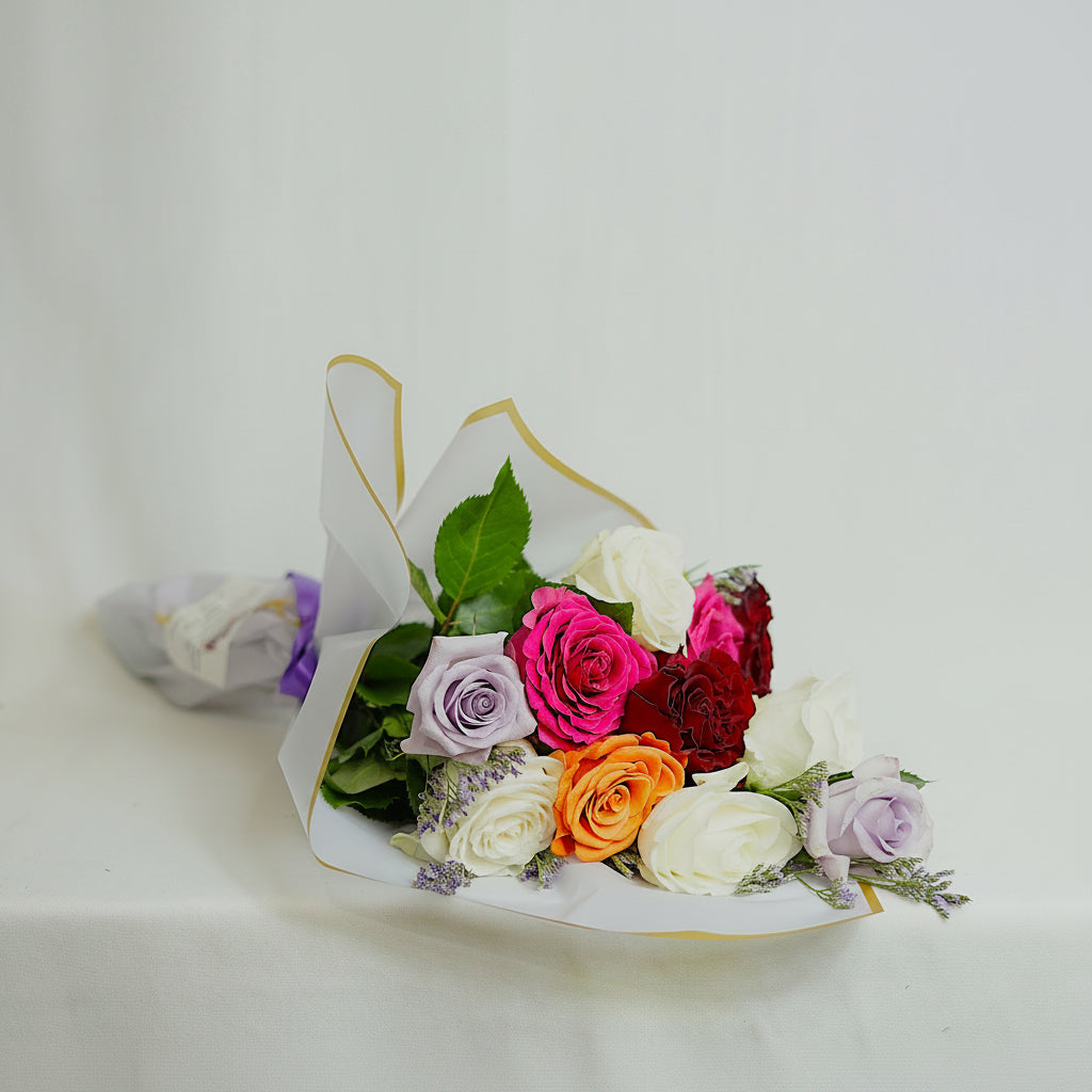 Bouquet of colorful flowers in a white paper wrap on a light background