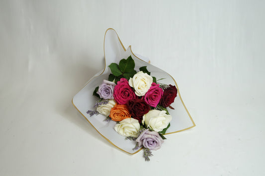 Colorful bouquet of flowers in a decorative paper cone on a white background