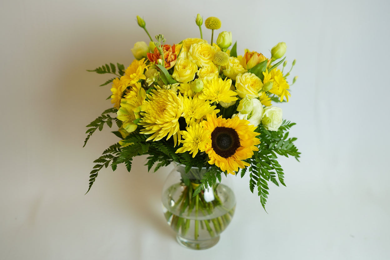 Bouquet of yellow flowers with green leaves on a light background